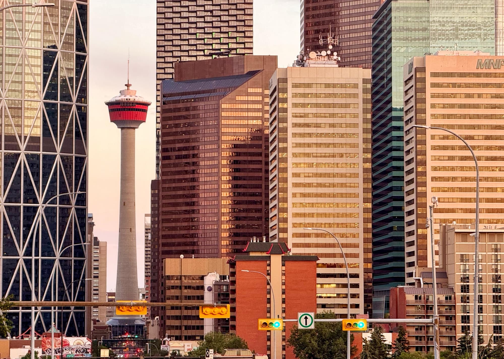 Golden hour skyline of large buildings with the distinctive Calgary Tower in between