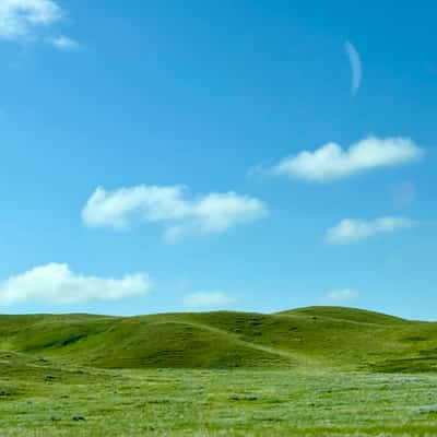 Rolling green hills under a mottled blue sky