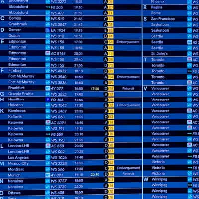 Blue airport departure board heavy with Canadian destinations organized first alphabetically by city of arrival, then by time