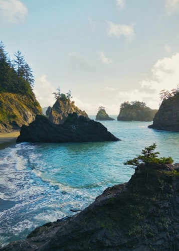 Tree-topped rocky islands jutting out of an aquamarine ocean