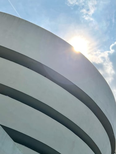 Sweeping curved building lines with the bright sun poking up from the top edge