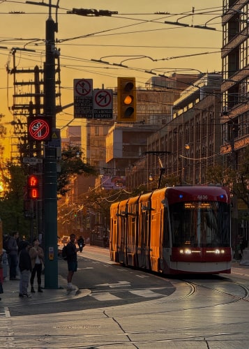 Orange-tinted streetcar in a busy urban center