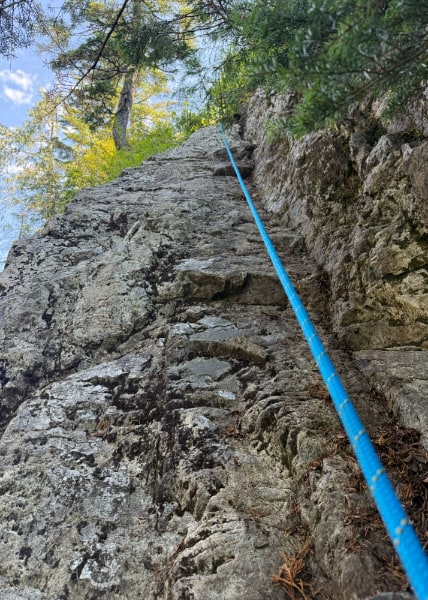 Looking up a fairly sheer cliff face with a blue rope running down the length of it