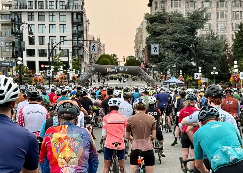 Large crowd of cyclists at the start line on a city street with older buildings and ornate street lamps