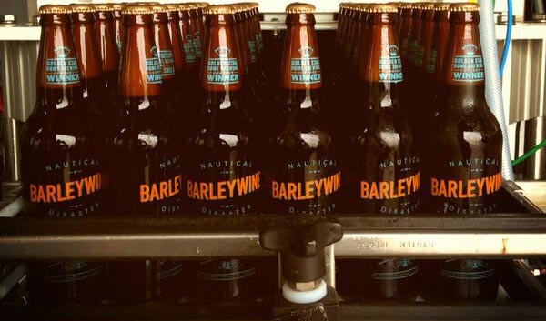 Brown-toned photo of many identical bottles of beer held by an apparatus that has arranged them in a 6x6 grid