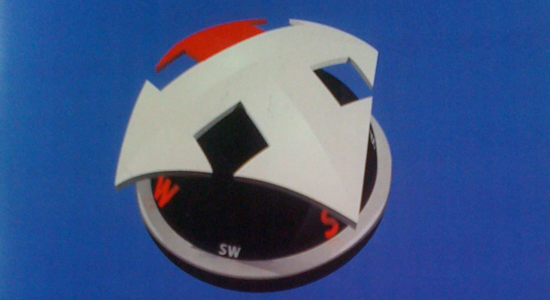 Photo of a poster featuring a black and white spherical compass with orange details and a 4-way arrow atop pointing toward North